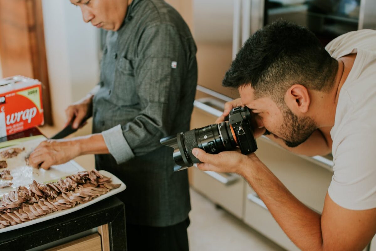 who-we-are A photographer captures a chef slicing meat on a tray in a kitchen setting.