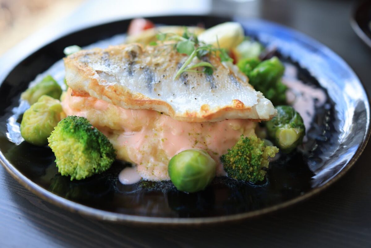Delicious fish fillet served with broccoli, Brussels sprouts, and creamy sauce.