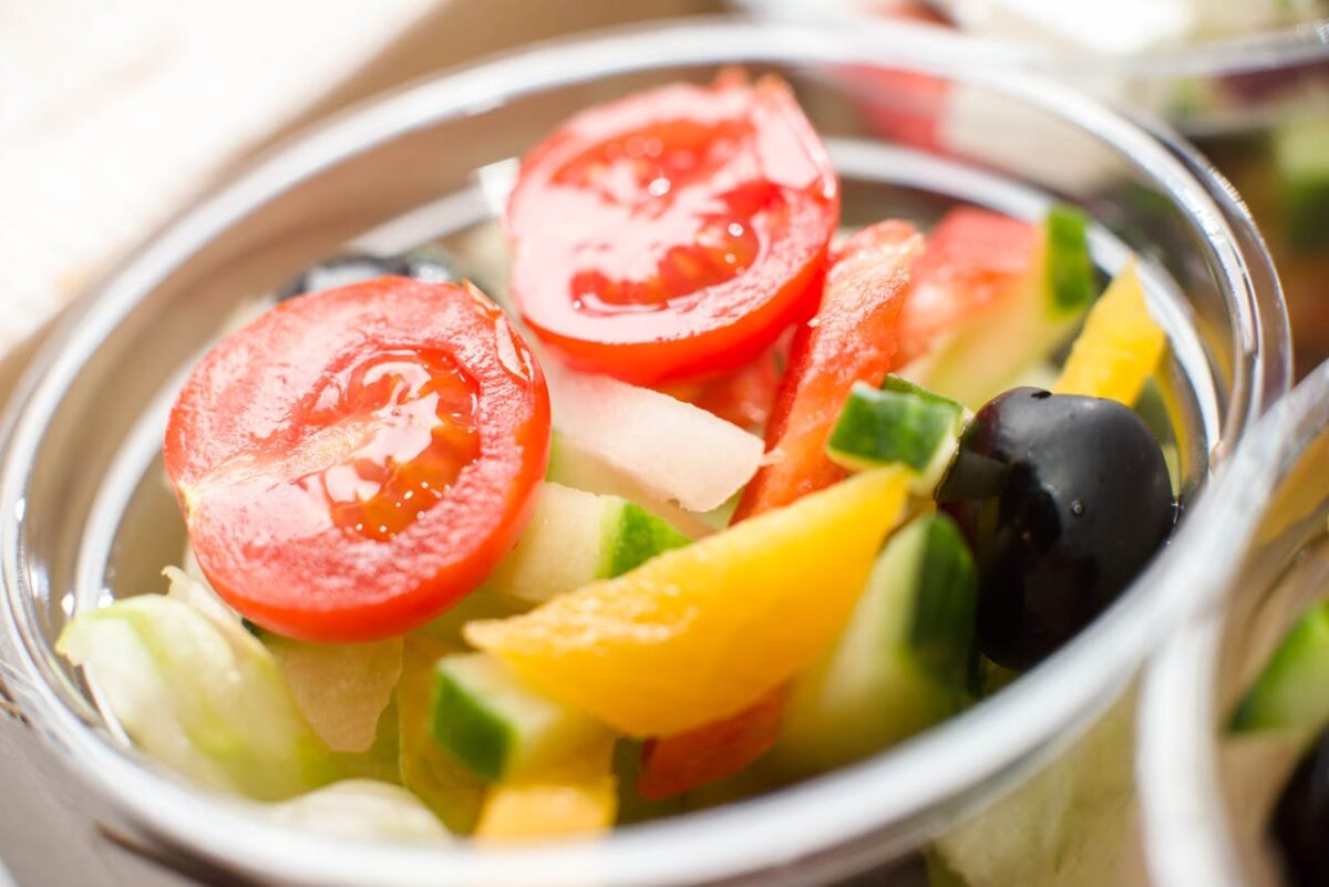 why-choose-us Vibrant vegetable salad with tomatoes, cucumber, and olives in a bowl. Perfect for healthy eating.