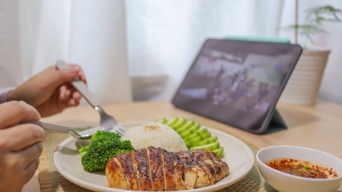 A person enjoys a healthy meal with technology entertainment. Perfect for lifestyle or food topics.